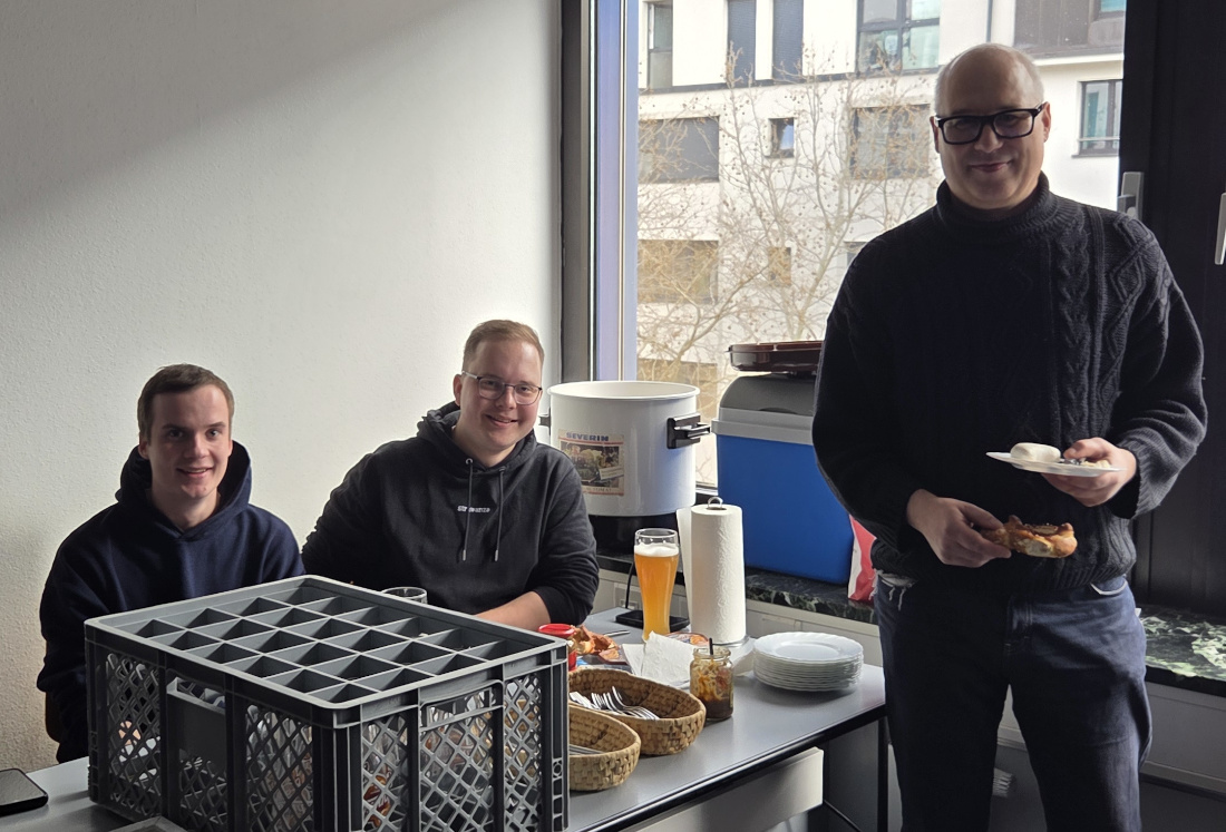 Zwei Schüler und ein Dozent vor dem Weisswurstkessel